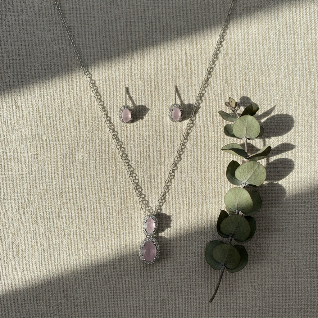 Rose quartz jewelry set on beige linen with eucalyptus