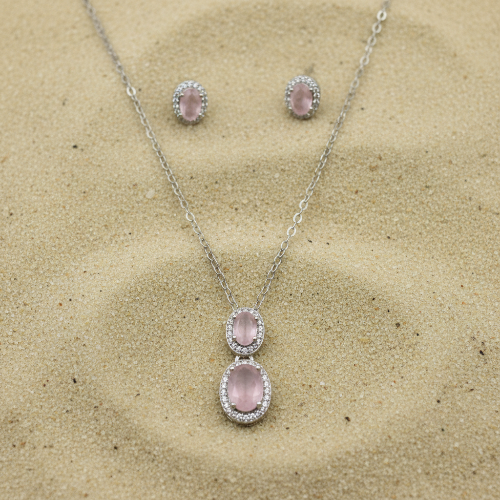 Rose quartz jewelry set on sand background with studio lighting